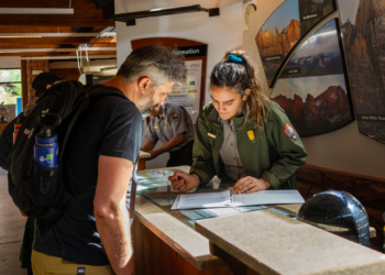 Ranger Emily Gamboa helps a visitor at the information desk at Zion National Park in Utah. PHOTO COURTESY OF ABI FARISH/ NPS